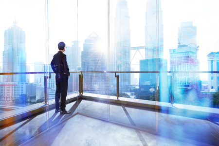 Young businessman looking out the city in the office . morning scene. .の写真素材