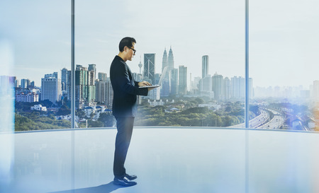 Businessman using laptop with generic office background , night scene .の写真素材