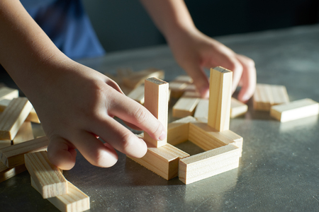 Hand of kid playing a blocks wood tower game of architectural project .Selected focusing .の写真素材