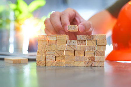 Hand of engineer playing a wood block . Growth in business and goal concept.の写真素材