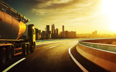 Truck on the road with  motion blur with city skyline background . Sunset scene .の写真素材
