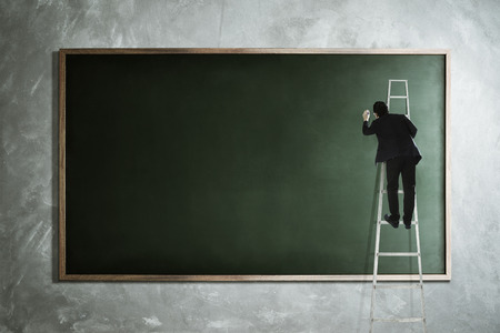 Men drawing on empty blackboard .の写真素材
