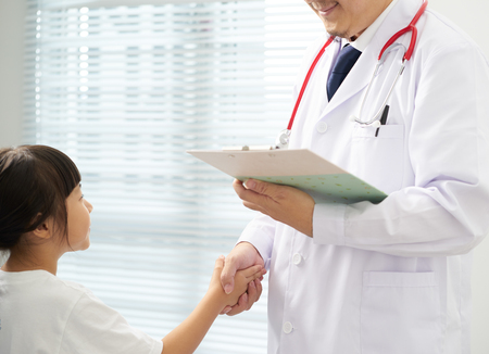 Unknown smile and friendly doctor and happy little girl shaking hands .の写真素材