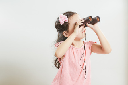 Beautiful little young cute asian girl using telescope looking for something .の写真素材