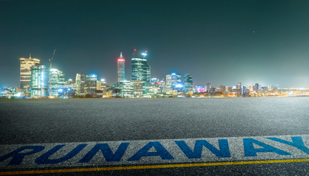 View of the empty asphalt road with runawy word and city skyline background . Night scene .の写真素材