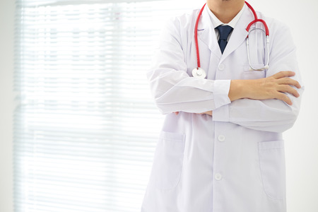 Unknow doctor posing with arms crossed in the office, he is wearing a stethoscope .の写真素材