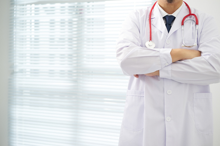 Unknow doctor posing with arms crossed in the office, he is wearing a stethoscope .の写真素材