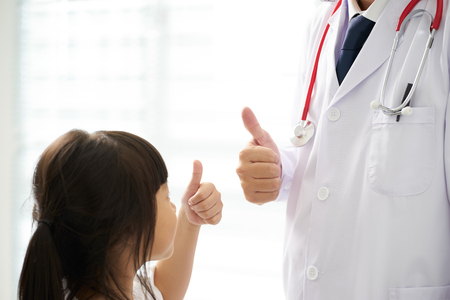 Unknown doctor and little girl hands with thumbs up .の写真素材