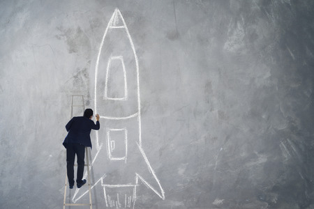 Businessman climb stair drawing rocket sketch on wall , Success, leader and winner concept .の写真素材