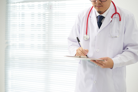 Doctor with a stethoscope and taking notes with bright background .の写真素材