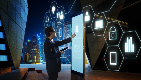 Businessman touching "Money" sign on screen of digital booth with fintech infographic icon . Hi-tech business concept .の写真素材