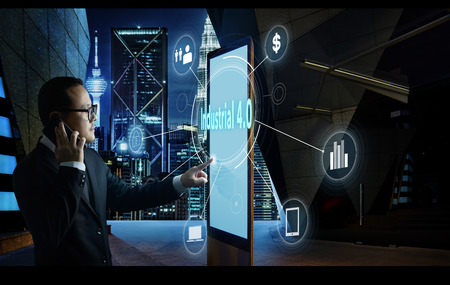 Businessman touching "Industrial 4.0" word on screen of digital booth with fintech infographic. Hi-tech business concept .の写真素材