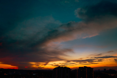 Beautiful natural sunset sunrise over silhouettes city skyline and amazing orange cloud blue sky above it .の写真素材