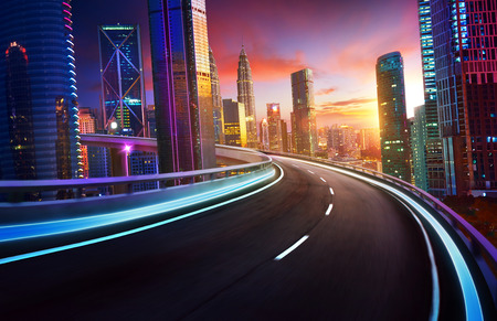 Highway overpass motion blur with city skyline and urban skyscrapers , sunset and twilight scene.の写真素材