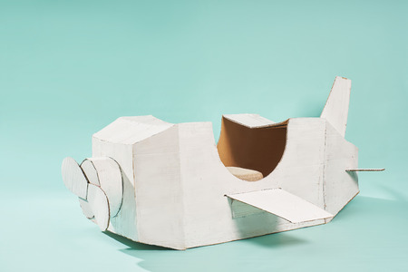 White retro style cardboard airplane on mint green background . Childhood fantasy imagination concept .の写真素材
