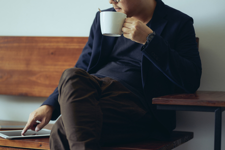 Closeup view of relaxing businessman using digital pad and drink the coffee .の写真素材