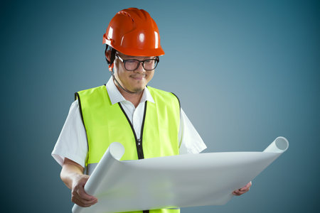 Portrait of professional construction contractor worker with hard hat and holding construction blue...