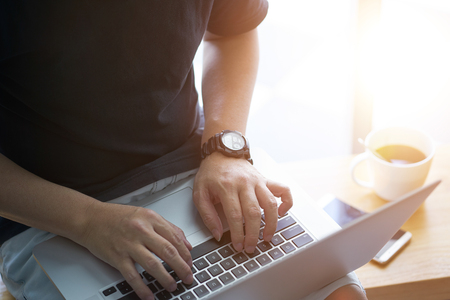 Laptop in businessman hand with smartphone and coffee .の写真素材