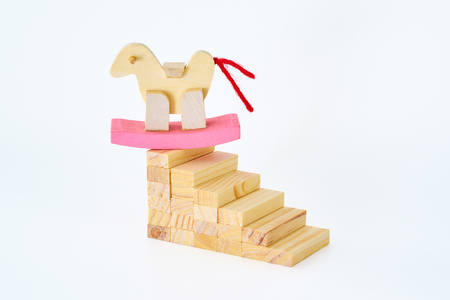 Wooden horse stand on top of wooden block stair isolated on white background ,concept of unswerving in business or education.の写真素材
