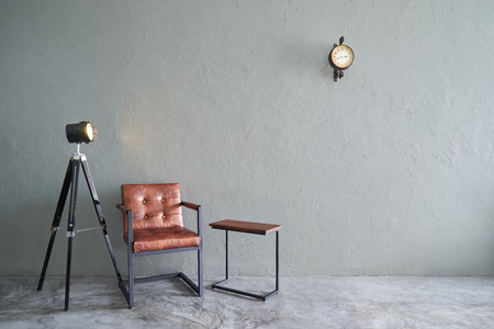 Modern living room with brown iron chair , clock ,tea table and lamp stand. cement floor and concrete wall ,Interior design with Loft style .の写真素材