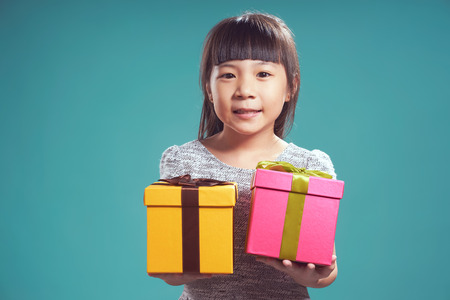 Close up portrait of asian little happy girl with two present box , isolated on light blue background . Vintage filter apply .の写真素材