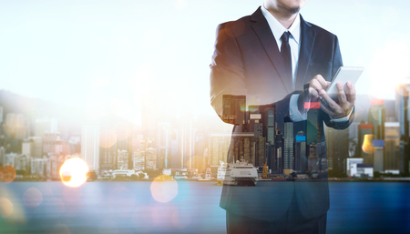 Portrait of businessman using smartphone.Double exposure effect with Hong Kong city skyline business center view at sunrise .の写真素材