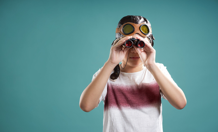 Smart kid using binoculars facing camera .の写真素材