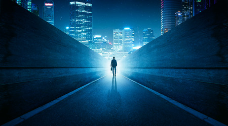 Ambitions concept with businessman walking from alley to modern city . Night scene .の写真素材