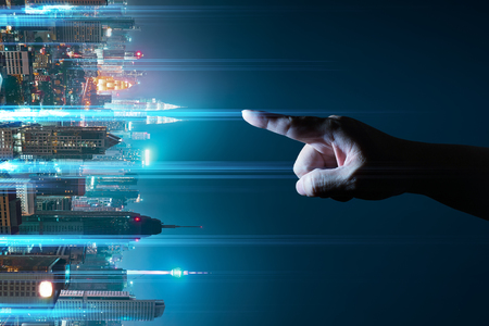 Unknown hand touching the light came out from the ground ,flip modern city background with wireless network connection concept , abstract communication technology image visual .の写真素材