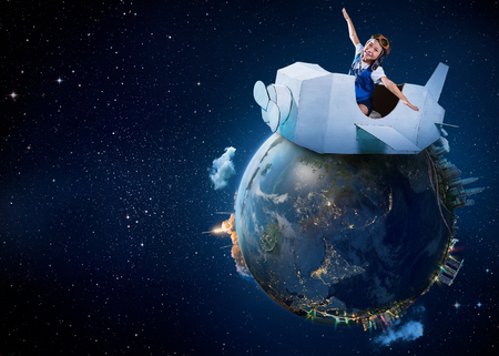 Little cute girl playing with a cardboard airplane with Earth planet background .Childhood dream imagination concept . .Extremely detailed imageの写真素材