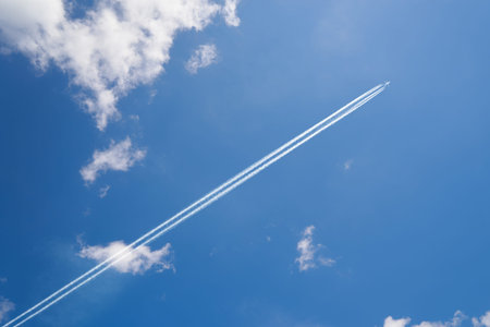 Airplane contrail against skyblue sky with white cloud .