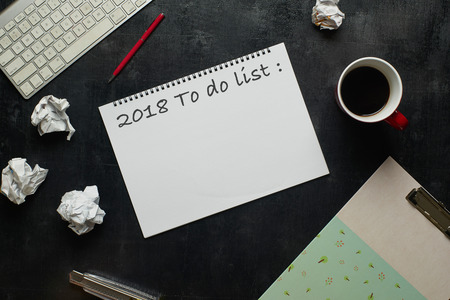 Keyboard, pen and other supplies with cup of coffee with text  2018 to do list. Wooden black office desk table with top view angle .の写真素材