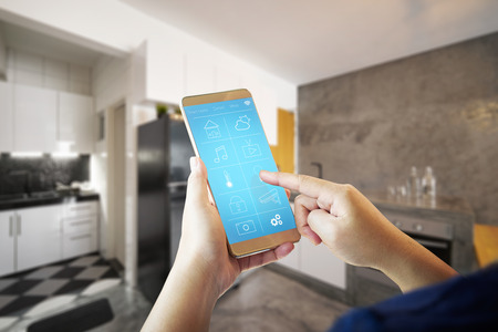 Female hand is adjusting lighting with smart phone. 
Smart home control concept.の写真素材