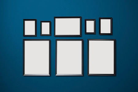 Eight empty picture frames hanging on the blue color wall .の写真素材