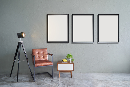 Modern living room with three empty picture frames, iron brown relax chair ,green plant , lamp stand , wooden tea table and clock. cement floor and concrete wall , Interior design with Loft style .の写真素材