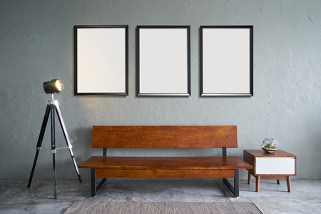 Modern living room with three empty picture frames, wooden bench sofa ,green plant , wooden tea table and clock. cement floor and concrete wall , Interior design with Loft style .の写真素材