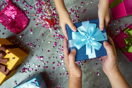 Close up hands of parent giving a  gift with colorful gift box and little star craft background . Present gifts ,Christmas ,New year seasonal holiday give concept .Top view .の写真素材