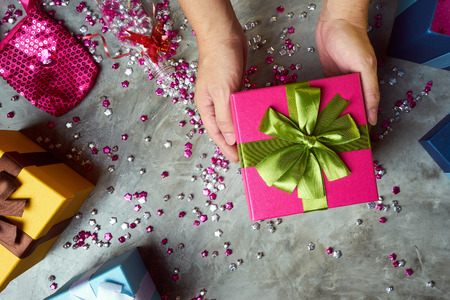 Close up hands of parent giving a Christmas gift with colorful gift box and little star craft background .  Cement texture desktop top view .の写真素材