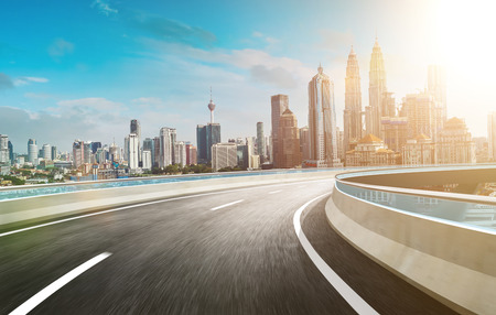 Motion curvy flyover asphalt highway road with modern cityscape skyline view  . Sunrise scene .の写真素材