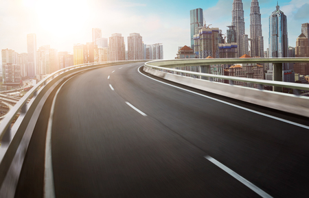 Motion curvy flyover asphalt highway road with modern cityscape skyline view  . Sunrise scene .の写真素材