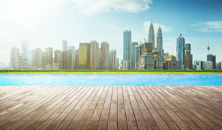 Wooden perspective brown empty floor in front of swimming pool with city skyline background .の写真素材