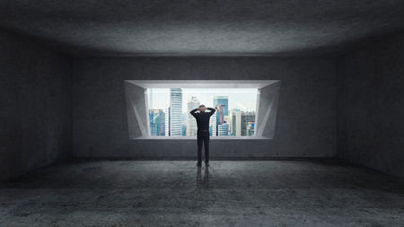 Thoughtful businessman standing in empty space concrete room with bright window and cityscape view . Mixed media .の写真素材