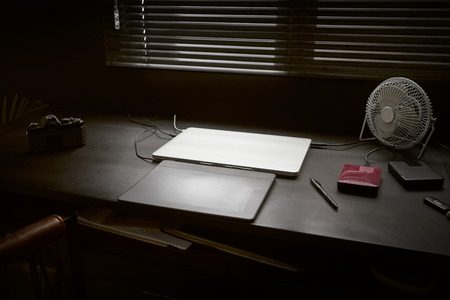 Work space on black table of a photographer or designer with laptop , retro camera and fan , Stylish home studio concept of hipster . Seleted focus.の写真素材