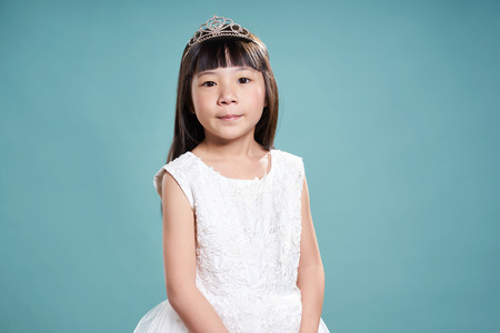 Portrait of little asian princess girl in silver crown and white dress isolated on vintage green background .の写真素材
