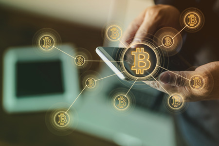 Closeup hand holding smartphone buy or sell virtual currency Bitcoin .
Electronic money ,blockchain transfers and finance concept.の写真素材