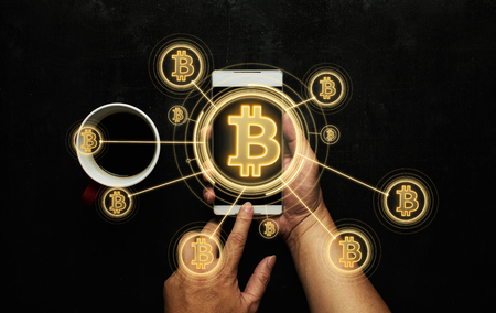 Closeup hand holding smartphone buy or sell virtual currency Bitcoin .
Electronic money ,blockchain transfers and finance concept.の写真素材