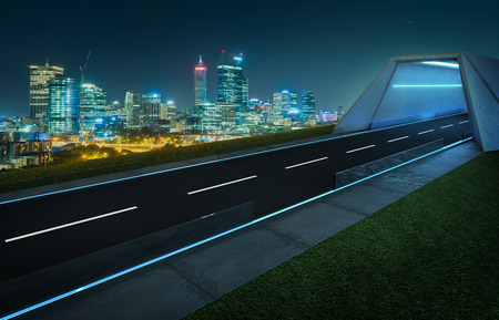 Empty asphalt road with tunnel ,greenfield and modern city skyline background . Mixed media .の写真素材