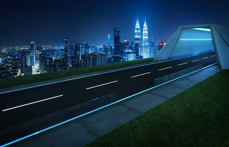 Empty asphalt road with tunnel ,greenfield and modern city skyline background . Mixed media .の写真素材