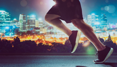 Close up of urban runner legs run on the night street .の写真素材