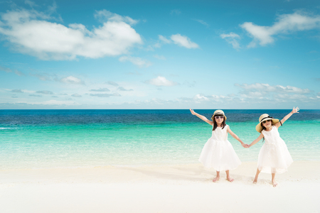 Portrait of happy asian sister at sandy beach in summer vacation .の写真素材
